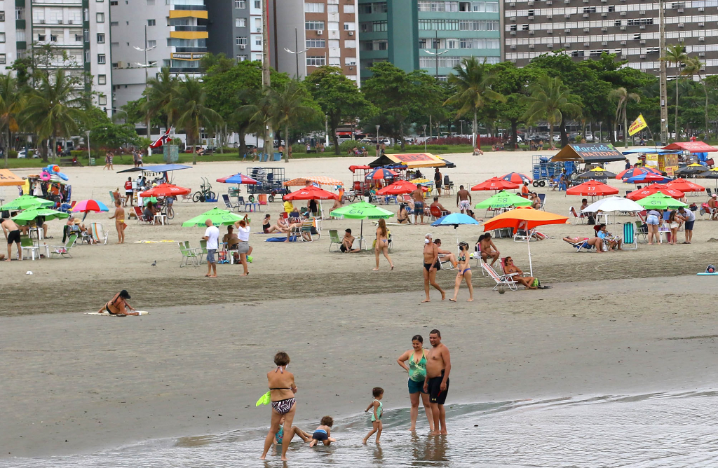 Apesar de céu nublado e garoa, banhistas enchem praias na Baixada Santista